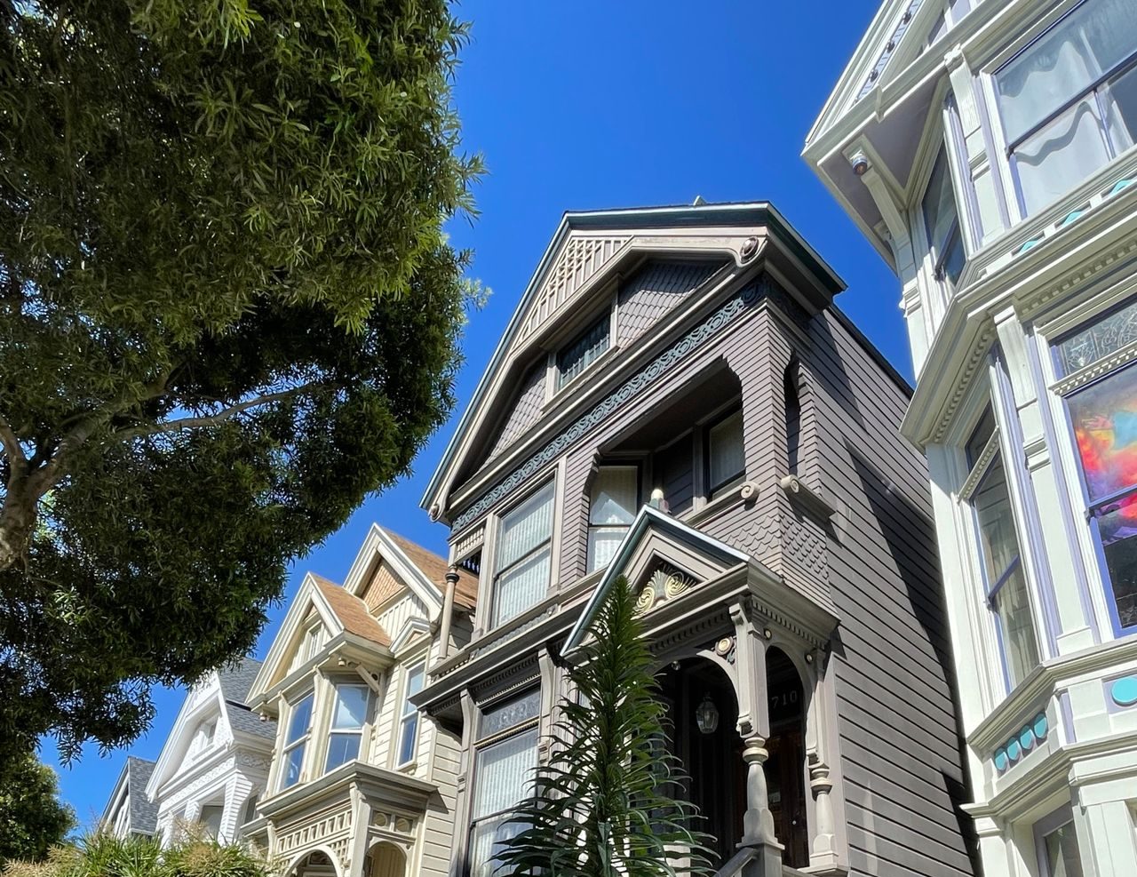 a tall Victorian-style home with ornate trim and a steep front staircasA