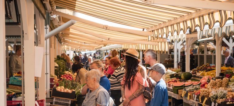 shoppers browsing an outdoor produce market along a lively downtown street