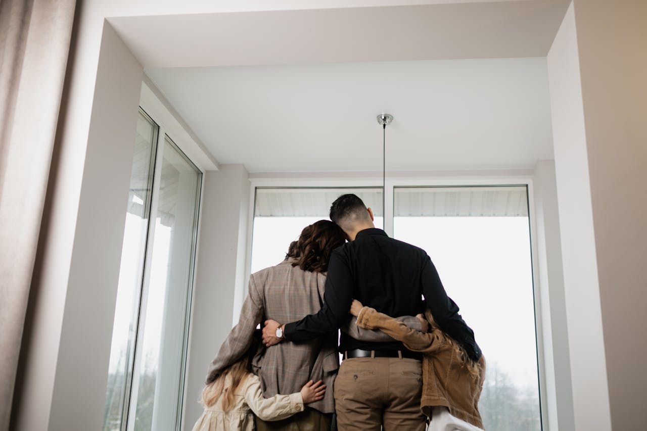 A family standing together in a bright, empty apartment after moving out