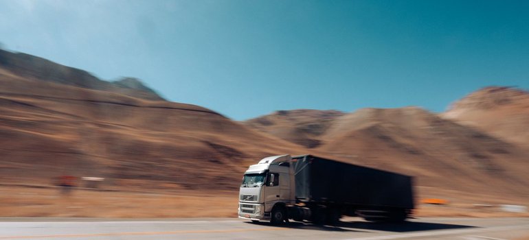 A large commercial truck driving down a highway past desert hills
