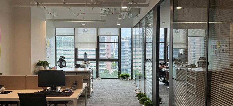 An open-plan office with desks and glass-walled meeting rooms