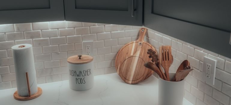 A clean white kitchen counter with a tiled backsplash and a few tidy essentials
