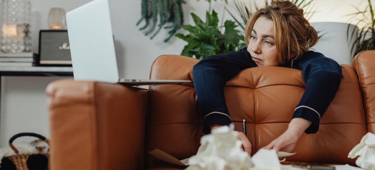 A woman waiting on a leather sofa next to an open laptop